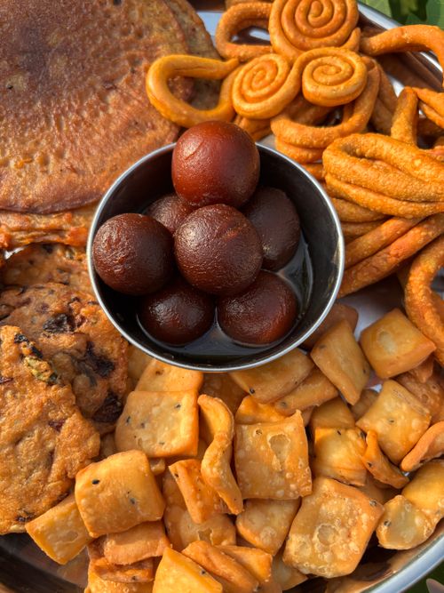Free Assorted Indian snacks and sweets including Gulab Jamun arranged artistically on a tray. Stock Photo