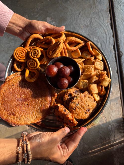Free A vibrant assortment of Indian snacks and sweets served on a platter in warm sunlight. Stock Photo