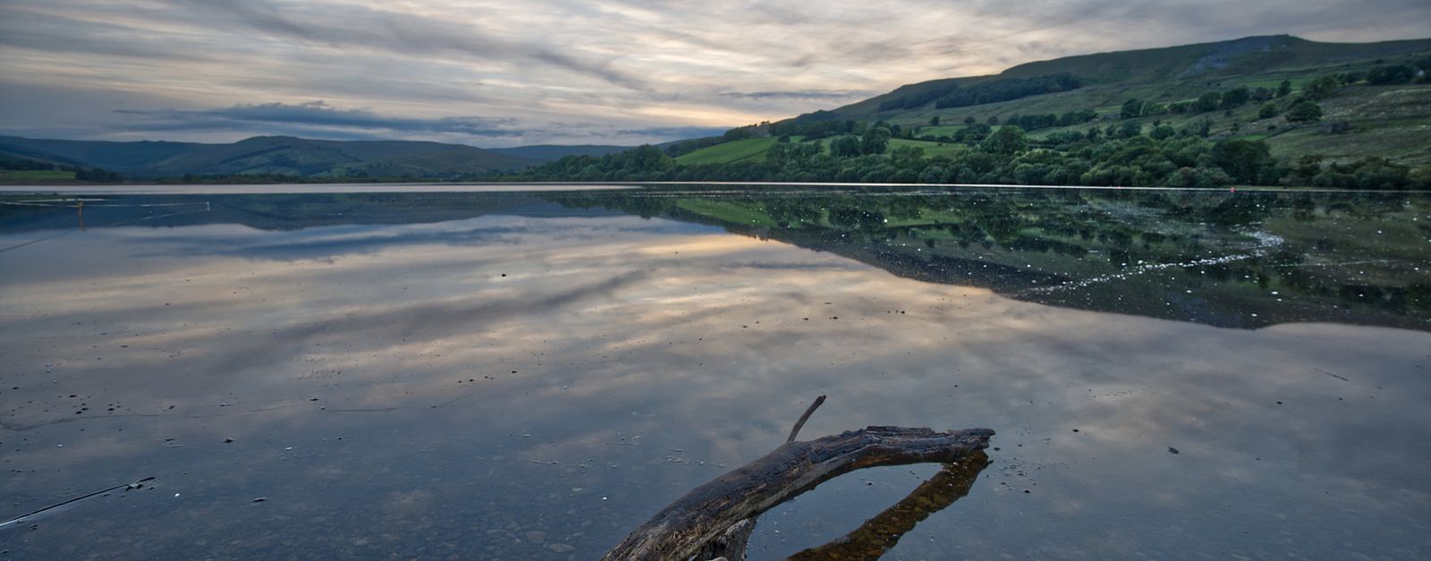 Tranquil lake scene with vivid sky reflections in England, captured at dusk.