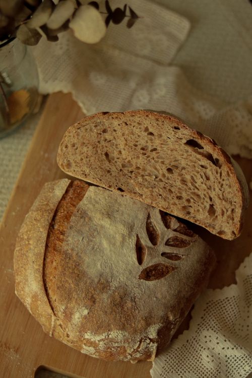 Free Beautifully crafted rustic bread loaf with artisan scoring on a wooden board, evoking a cozy homemade vibe. Stock Photo