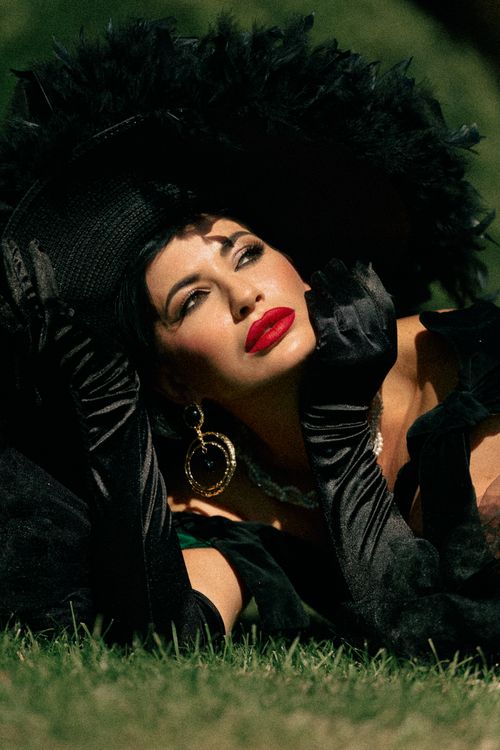 Free Elegant woman in black feathered hat with red lipstick posing outdoors, showcasing vintage glamour. Stock Photo
