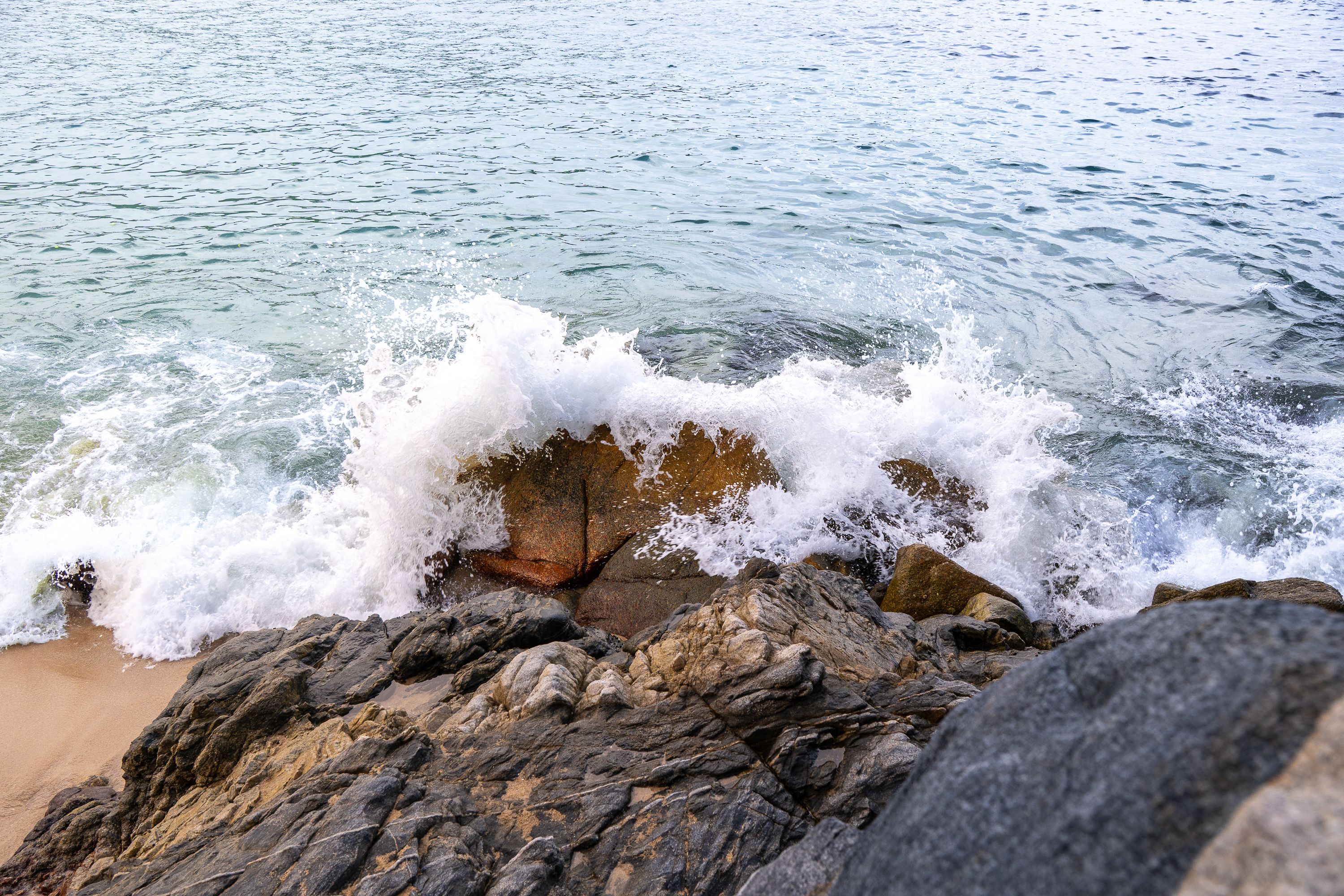 Dynamic ocean waves crash against rocks on the beach in Santa María Huatulco, Mexico, capturing nature's power.