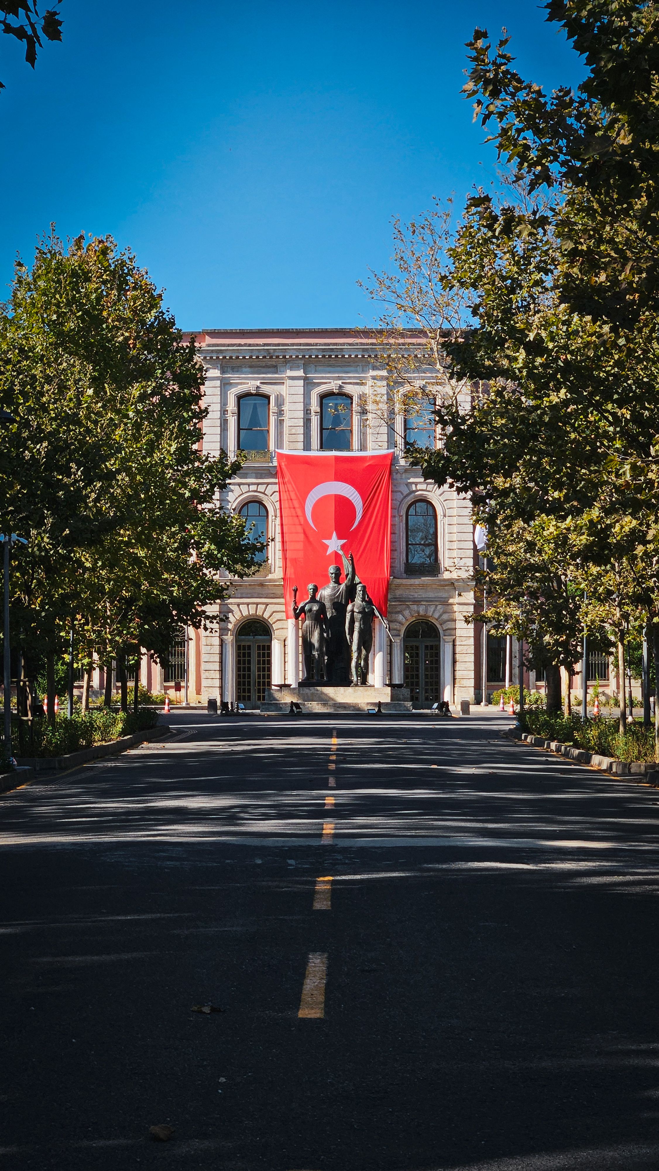 Istanbul University facade adorned with a large Turkish flag on a sunny day.