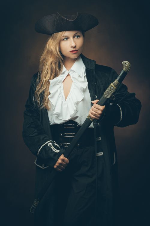 Free A woman dressed as a pirate holding a sword, evoking historical and adventurous themes. Stock Photo