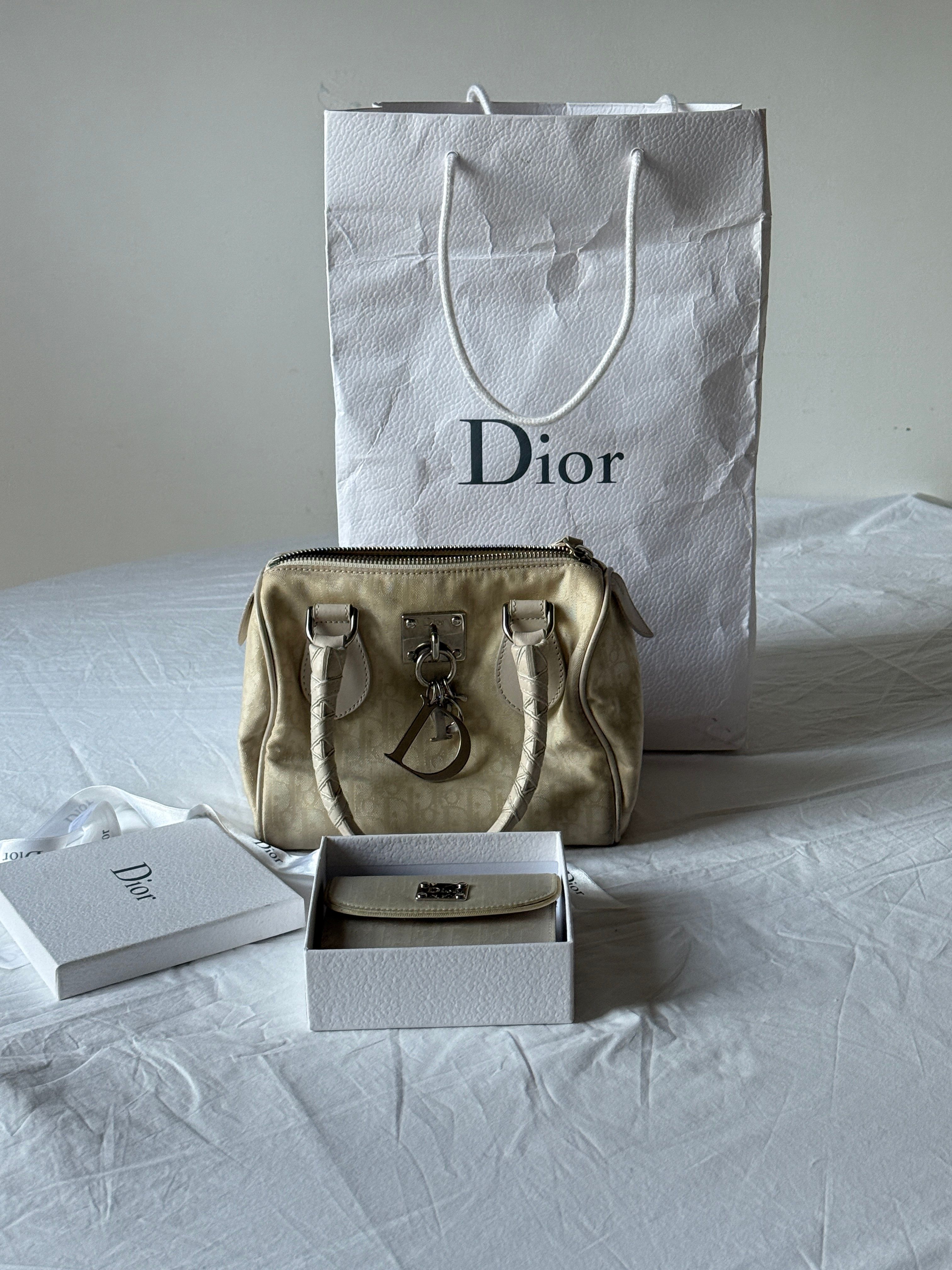 Elegante bolsa Dior exibida com embalagem e caixa da marca sobre uma superfície limpa, exalando luxo.