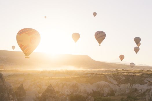 Hot air balloons ascending over Cappadocia's landscape during sunrise, capturing a breathtaking view of Türkiye's iconic region.
