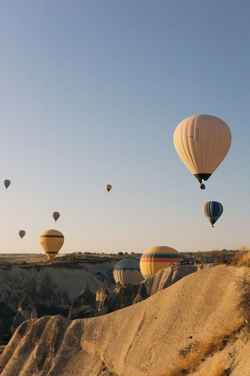 Free Vibrant hot air balloons soaring above Cappadocia's unique rock formations at sunrise. Stock Photo