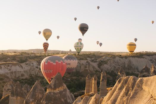 Stunning view of hot air balloons floating over Cappadocia's distinctive rock formations at sunrise.