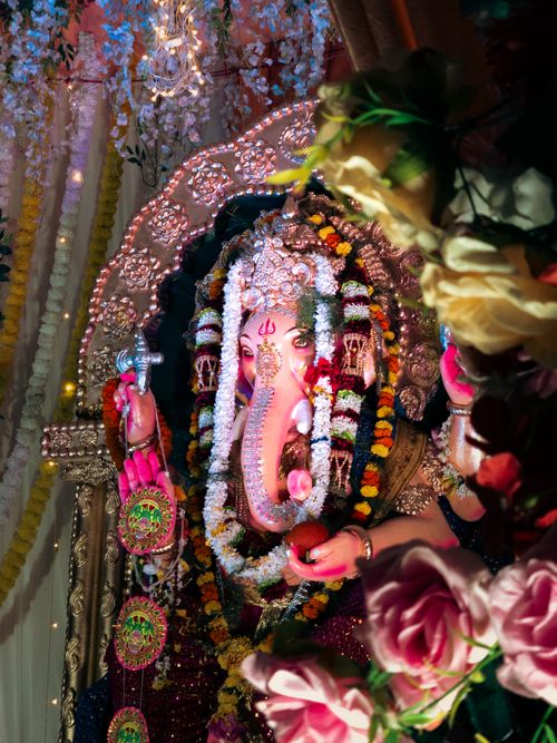 Free Close-up of a colorful Ganesh idol adorned with vibrant flowers and traditional decorations indoors. Stock Photo