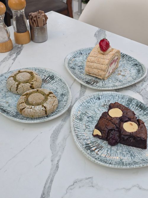 Free Delicious assortment of pastries including matcha cookies, roulade, and brownies on a marble table. Stock Photo