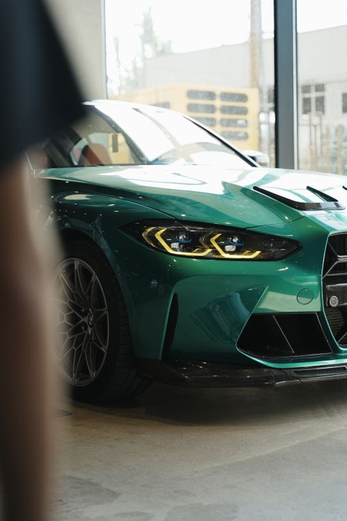 Free Front view of a green sports car displayed indoors in a modern showroom, emphasizing its sleek design. Stock Photo