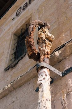 Close-up of a rusty metal hook with lace wrap mounted on a stone wall in Türkiye.