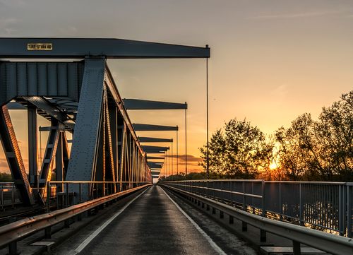 Free A picturesque view of a steel bridge at sunset, highlighting the vibrant colors of dusk and nature. Stock Photo