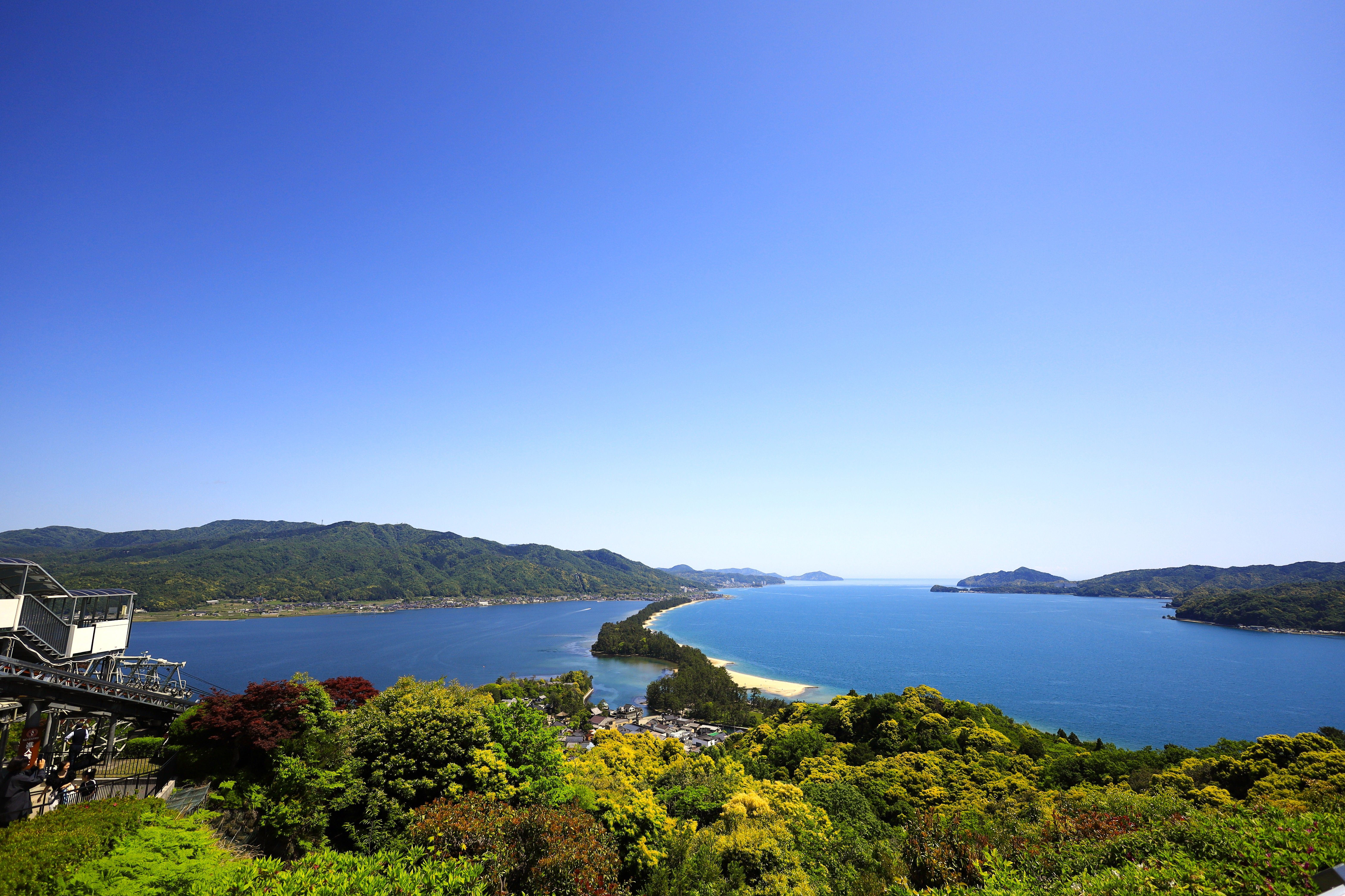Stunning aerial view of Amanohashidate sandbar surrounded by blue ocean and lush green mountains in Kyoto, Japan.
