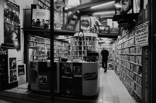 Free Monochrome view of a DVD store interior with a person browsing the shelves. Stock Photo