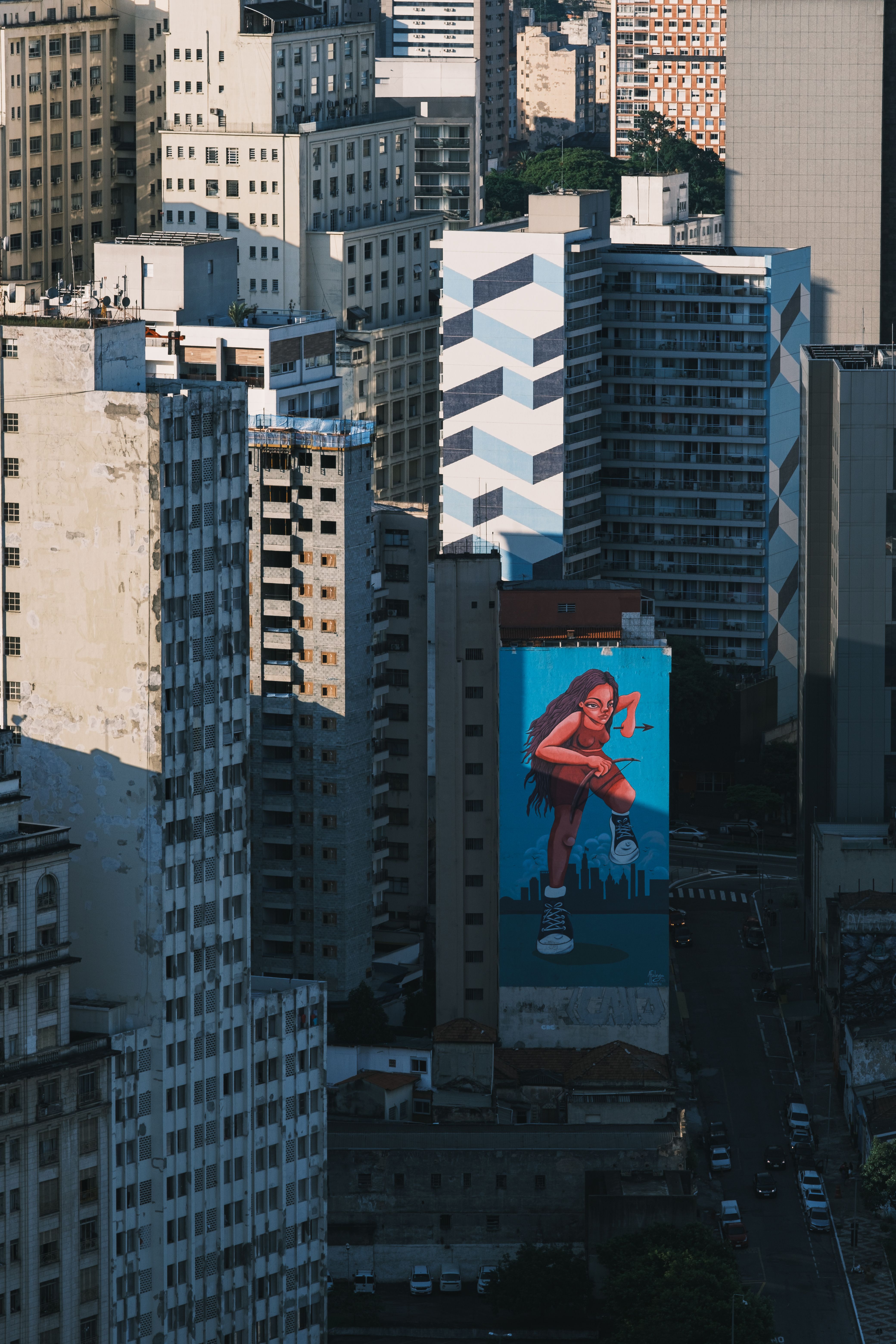 A vibrant mural of a dancer amidst high-rise buildings in an urban setting.
