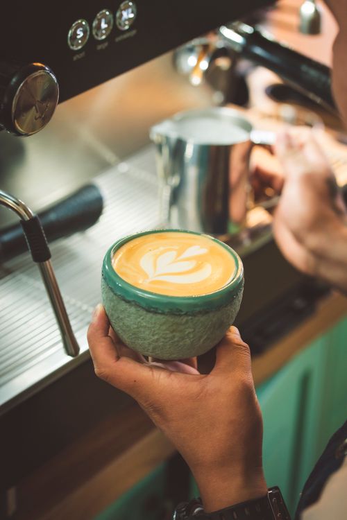 Free Barista creating latte art in a cozy cafe environment with espresso machine. Stock Photo