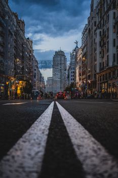 Gran Via in Madrid photographed at dusk, showcasing vibrant city life and towering architecture.
