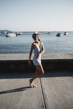 Stylish young woman enjoying a sunny day by the sea in Moda, Istanbul, with yachts in the background.