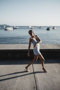 A young woman in a summer dress enjoying a sunny day by the marina.