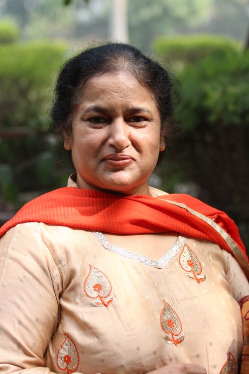 Free A portrait of an adult woman wearing a traditional outfit with a red scarf, captured outdoors. Stock Photo