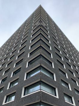 在多云的天空下，现代高层建筑以其引人注目的低角度透视和众多窗户显得格外醒目
