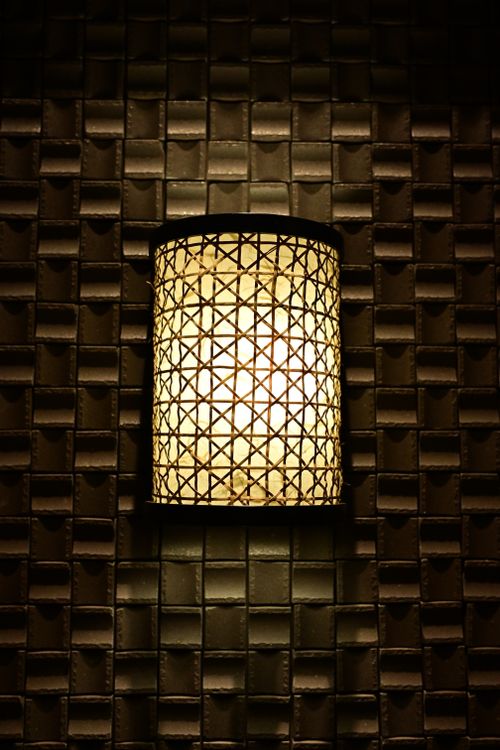 Free A warm ambient wall light illuminating a textured wall surface in a dark setting. Stock Photo