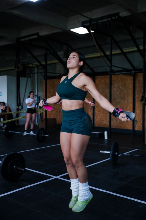 Free Energetic young woman performing jump rope exercise in a modern gym setting. Stock Photo