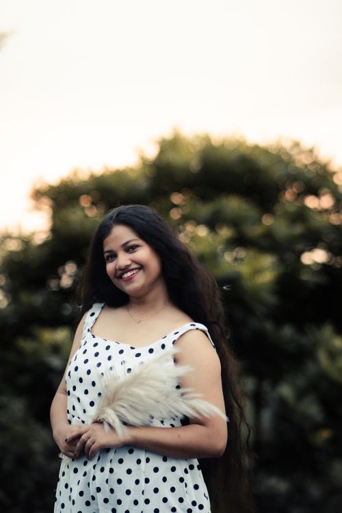 Free Portrait of a joyful woman in a polka dot dress, set against a lush outdoor backdrop. Captured at Baripada, India. Stock Photo