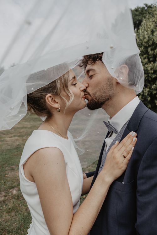 Free Bride and groom share a kiss under the veil during an outdoor wedding in Germany. Stock Photo