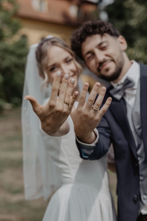 Free A happy couple joyfully showcasing their wedding rings in an outdoor setting, capturing a beautiful moment. Stock Photo