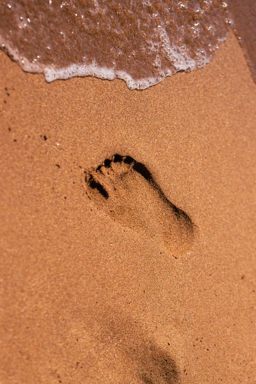 Free A single footprint on the sandy beach of Corfu, Greece, kissed by a gentle wave. Stock Photo