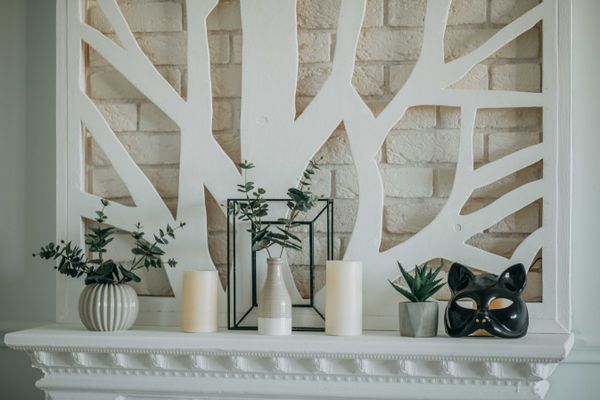 Pillar candles and greenery arranged along a painted mantelpiece. Photo by Natalie Bond on Pexels