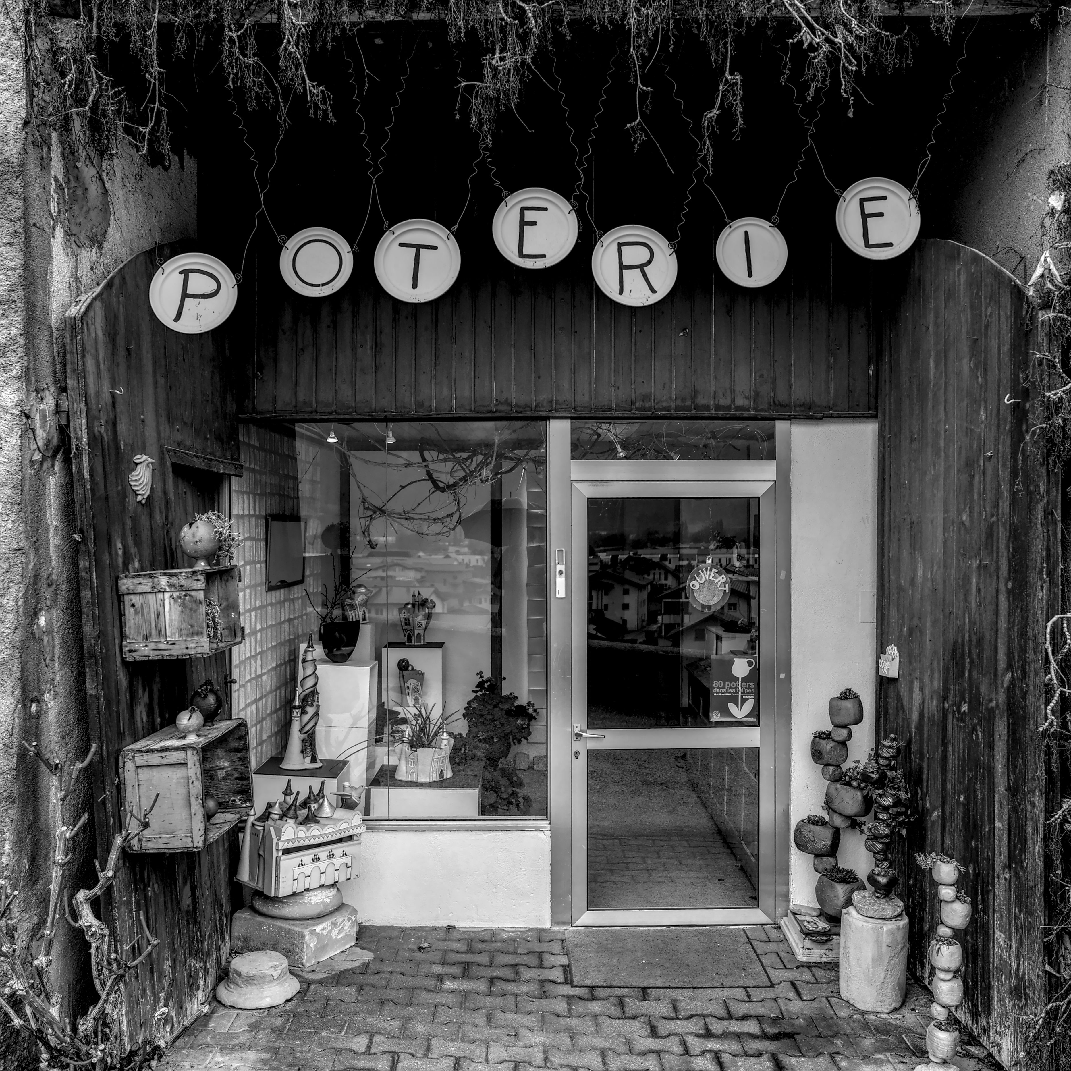 Black and white photo of a pottery shop entrance, showcasing artisanal ceramics.
