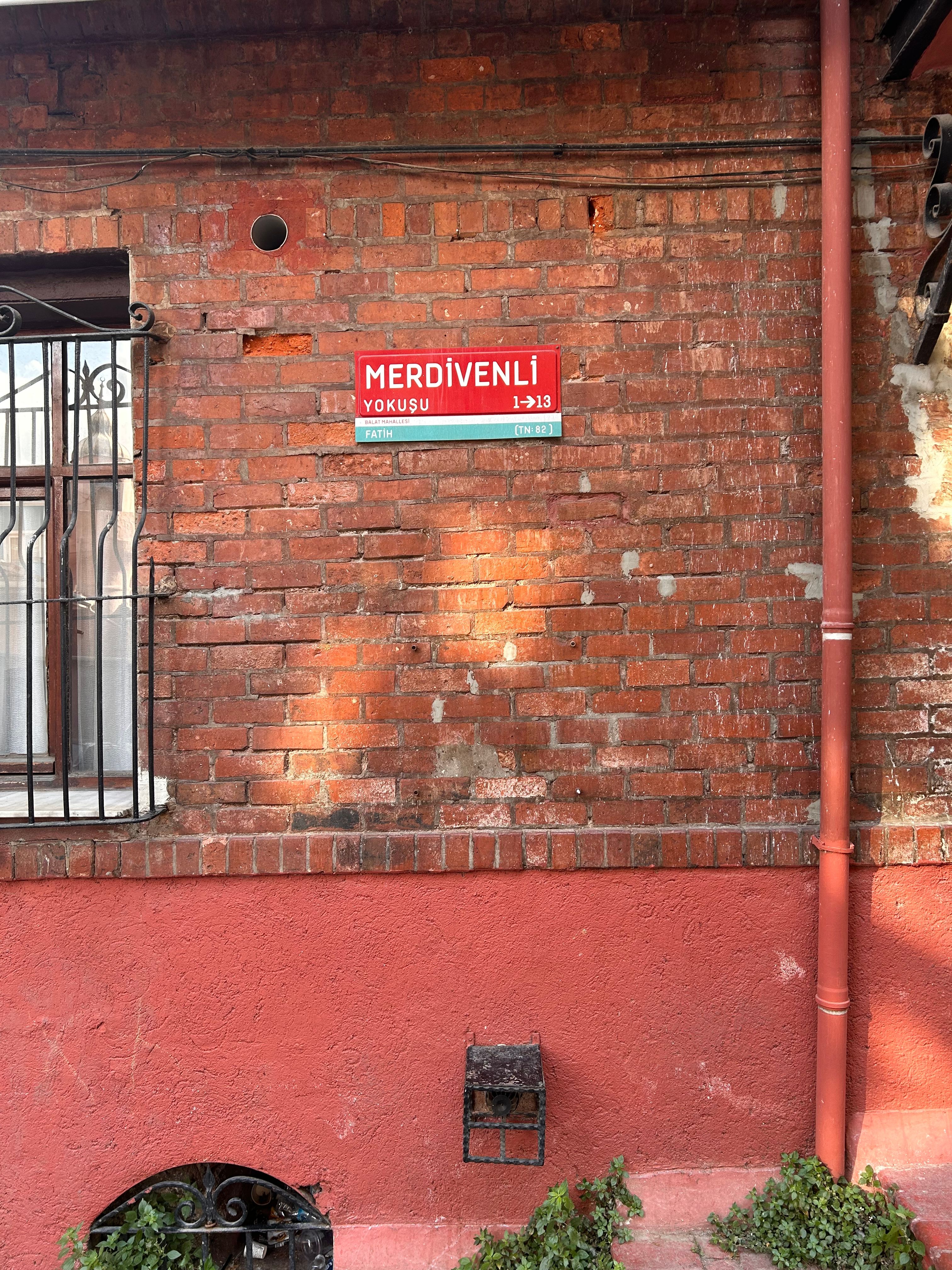 A charming red brick wall with Merdivenli Yokuşu street sign in İstanbul.