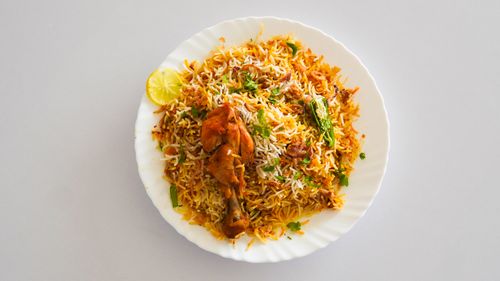 Free Top view of flavorful chicken biryani served with lemon slice on a white plate. Stock Photo
