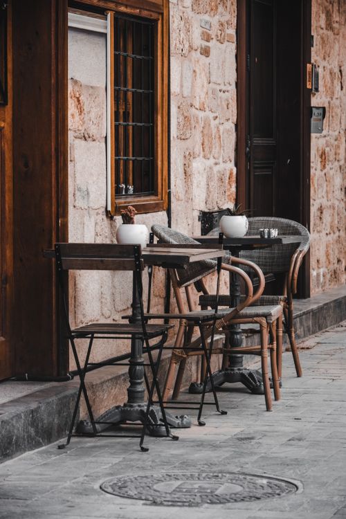 Free Cozy outdoor cafe with rustic wooden chairs and stone walls, creating an inviting atmosphere. Stock Photo
