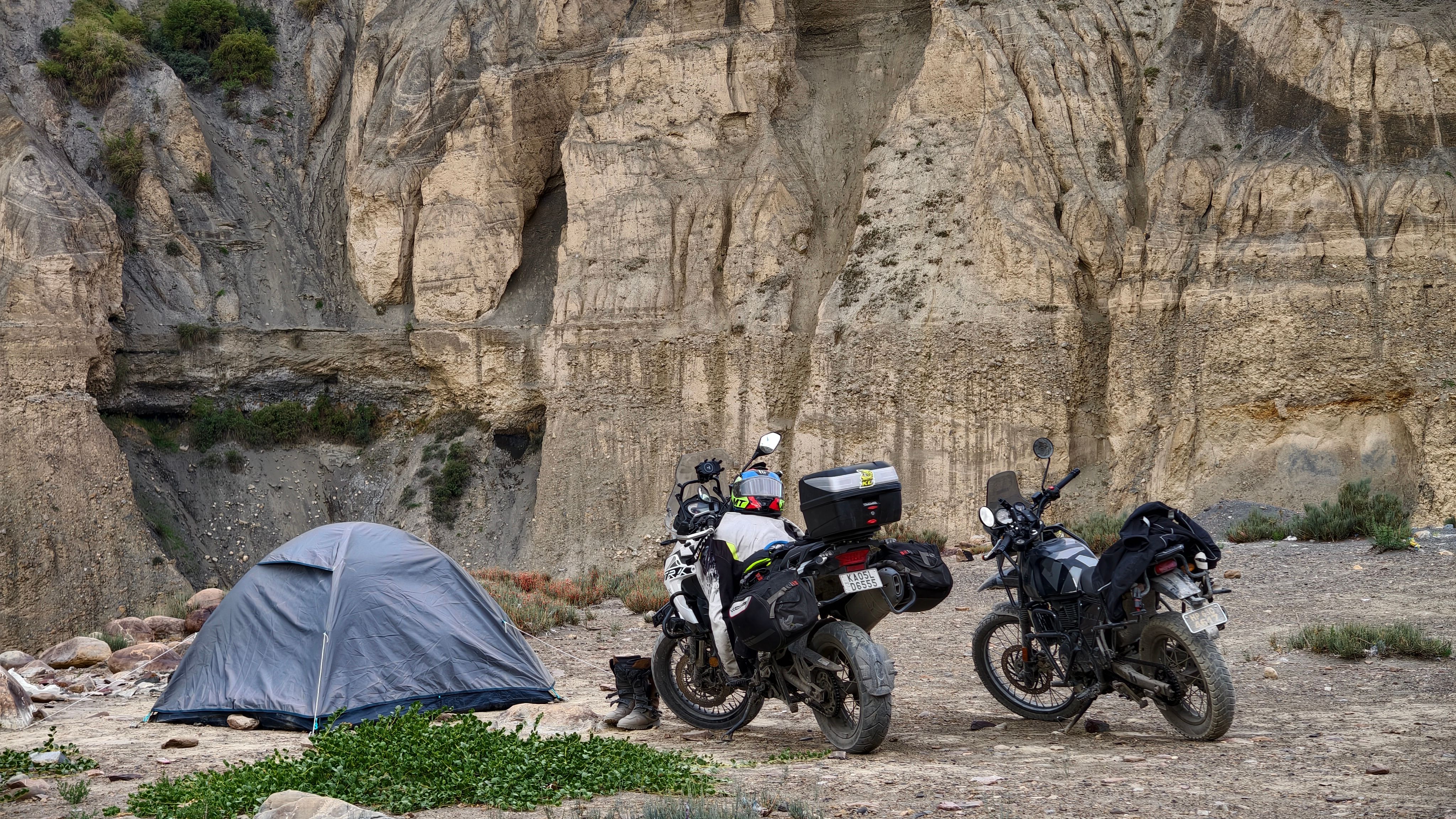 Motorcycles parked by a tent in the rugged landscape of Langza, Himachal Pradesh, India.