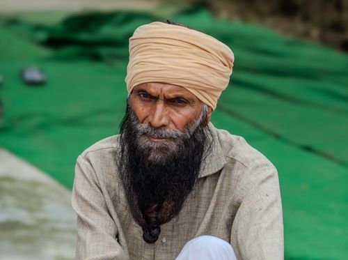 Free Portrait of an elderly man with a turban and long beard sitting outdoors, showcasing ethnic attire and cultural heritage. Stock Photo