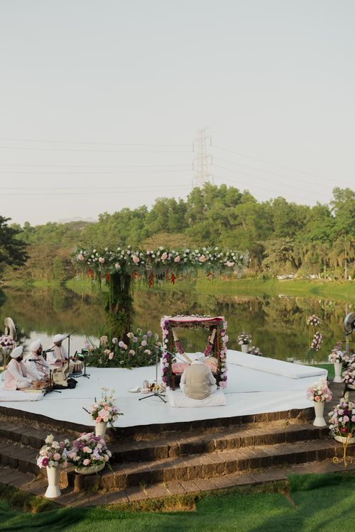 Free An elegant outdoor wedding ceremony by a tranquil lake with floral decor. Stock Photo