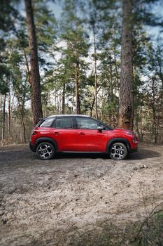 Red Citroen car parked in a lush forest near Kyiv, Ukraine.