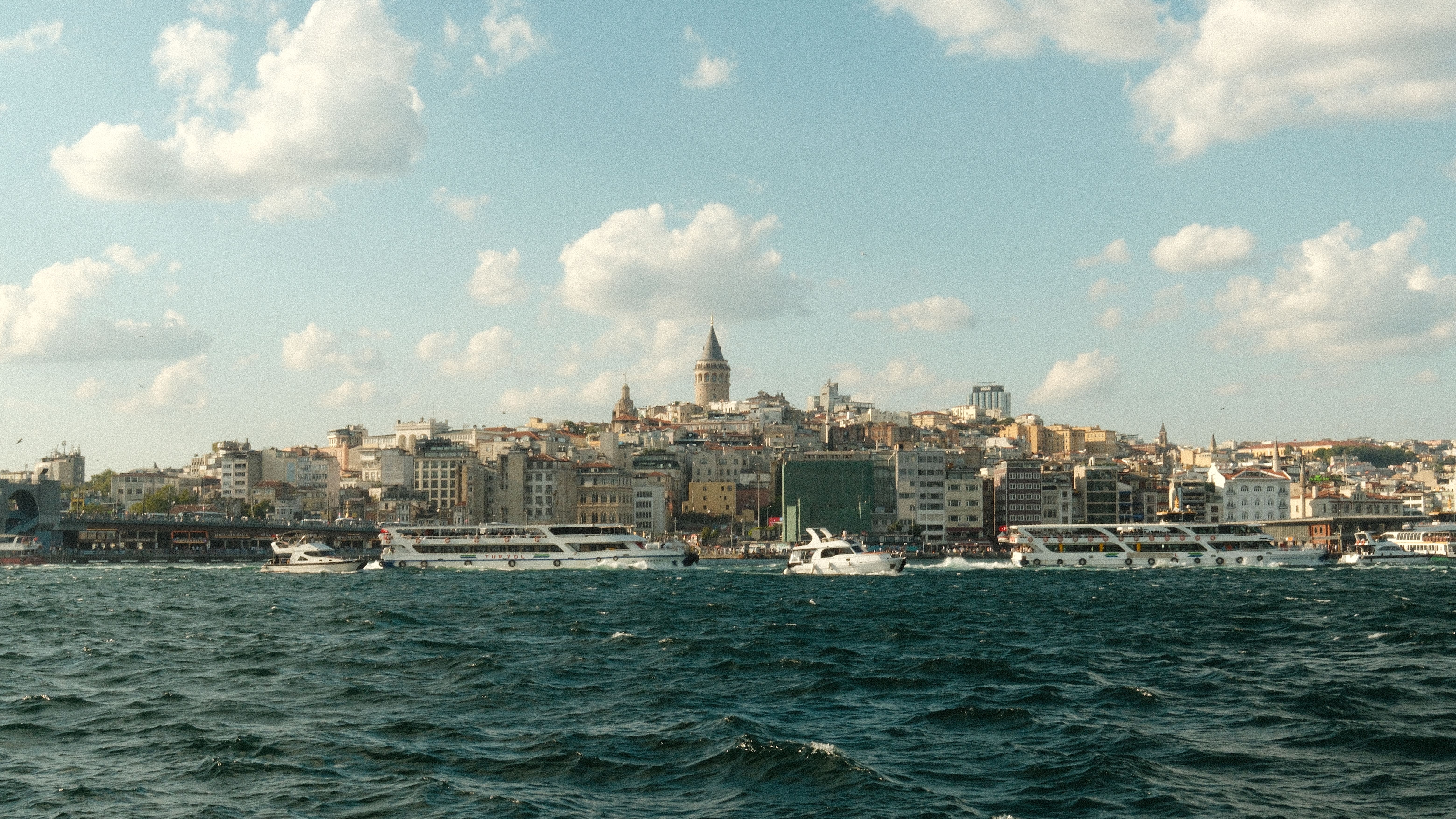 Panoramic view of Istanbul's Galata Tower and skyline across the Bosphorus strait on a sunny day.