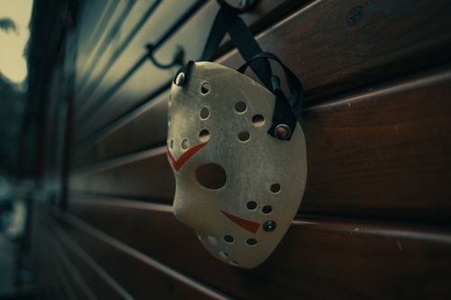 Free A hockey mask hangs on a wooden cabin wall, evoking a chilling horror movie atmosphere. Stock Photo