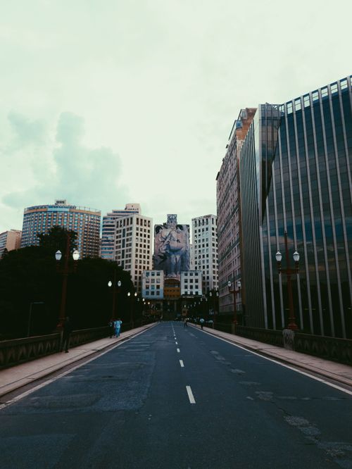 Free A broad, empty street flanked by tall modern buildings in a city. Stock Photo