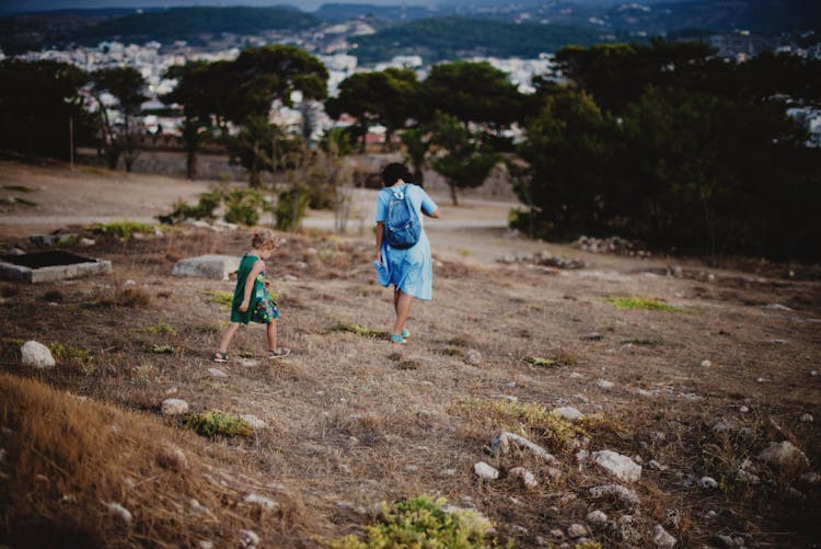 Mother And Daughter Walking Along Dry Hills At Countryside