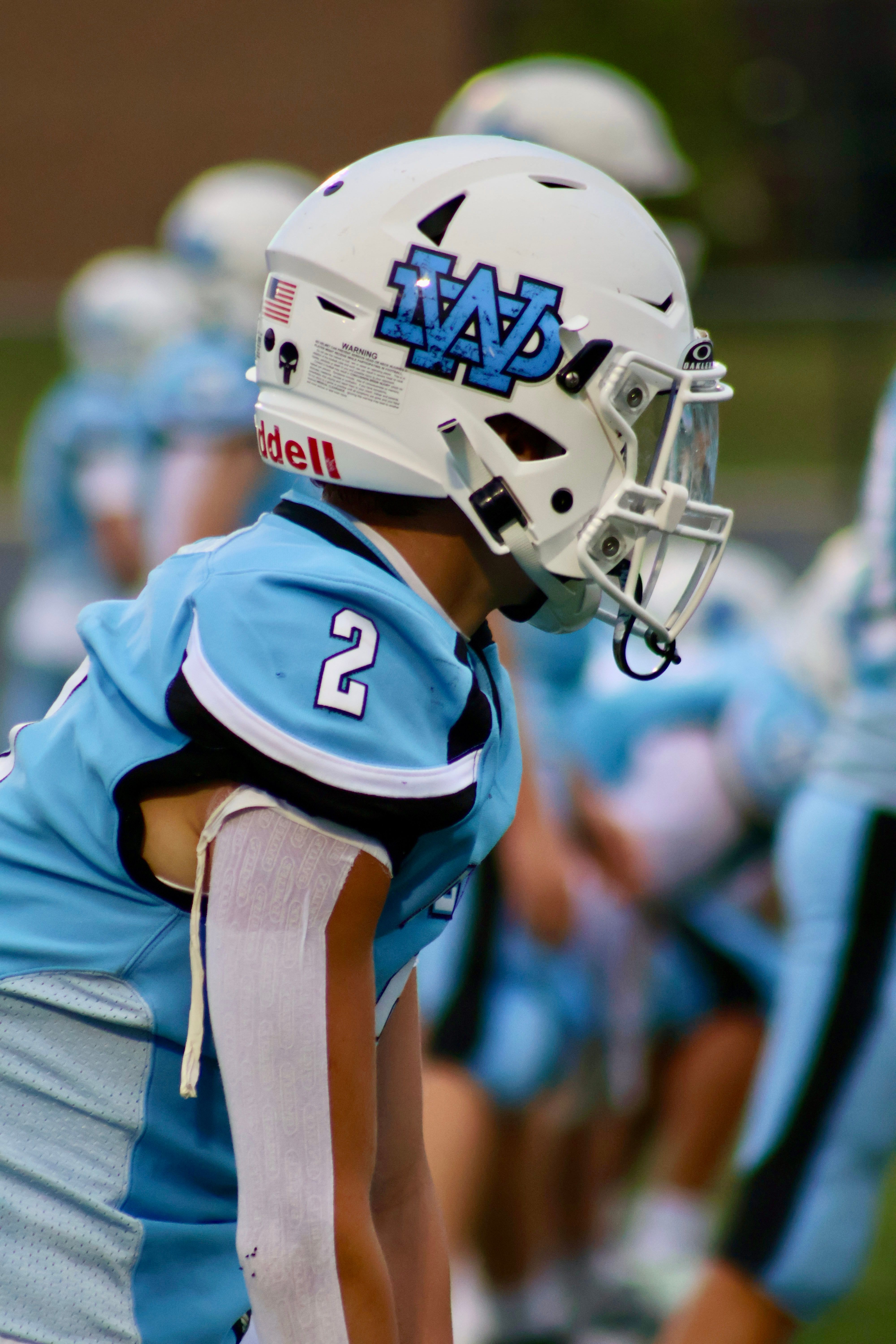 High school football player focused on the game, wearing blue and white uniform and helmet.