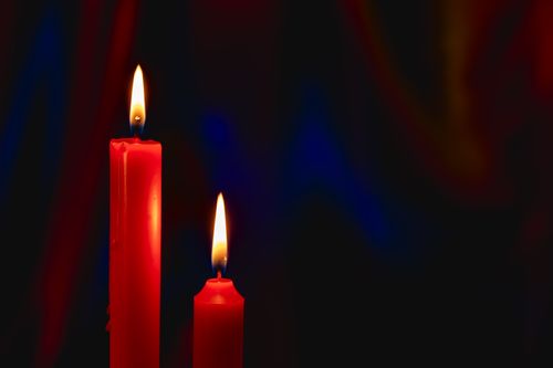 Free Two red candles burning brightly against a dark background, creating a serene atmosphere. Stock Photo