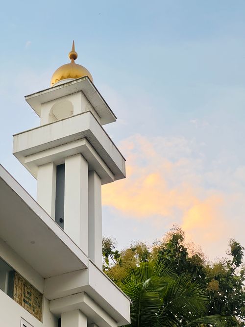 Free Beautiful mosque minaret with golden dome under colorful sunset skies, illustrating peaceful evening scenery. Stock Photo