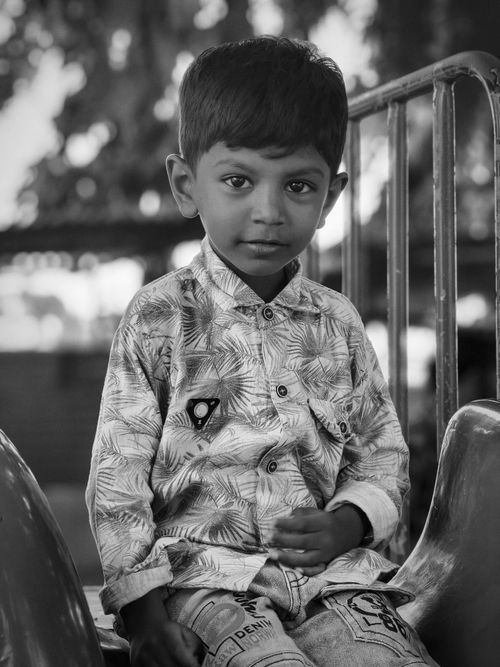 Free Black and white portrait of a young boy sitting and looking at the camera. Stock Photo