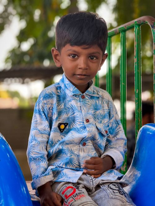 Free A young boy sitting on a colorful playground slide on a sunny day. Stock Photo